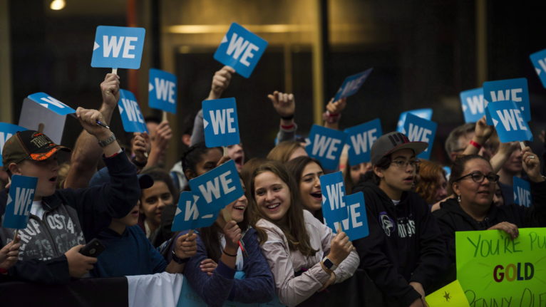 A crowed of people holding WE signs