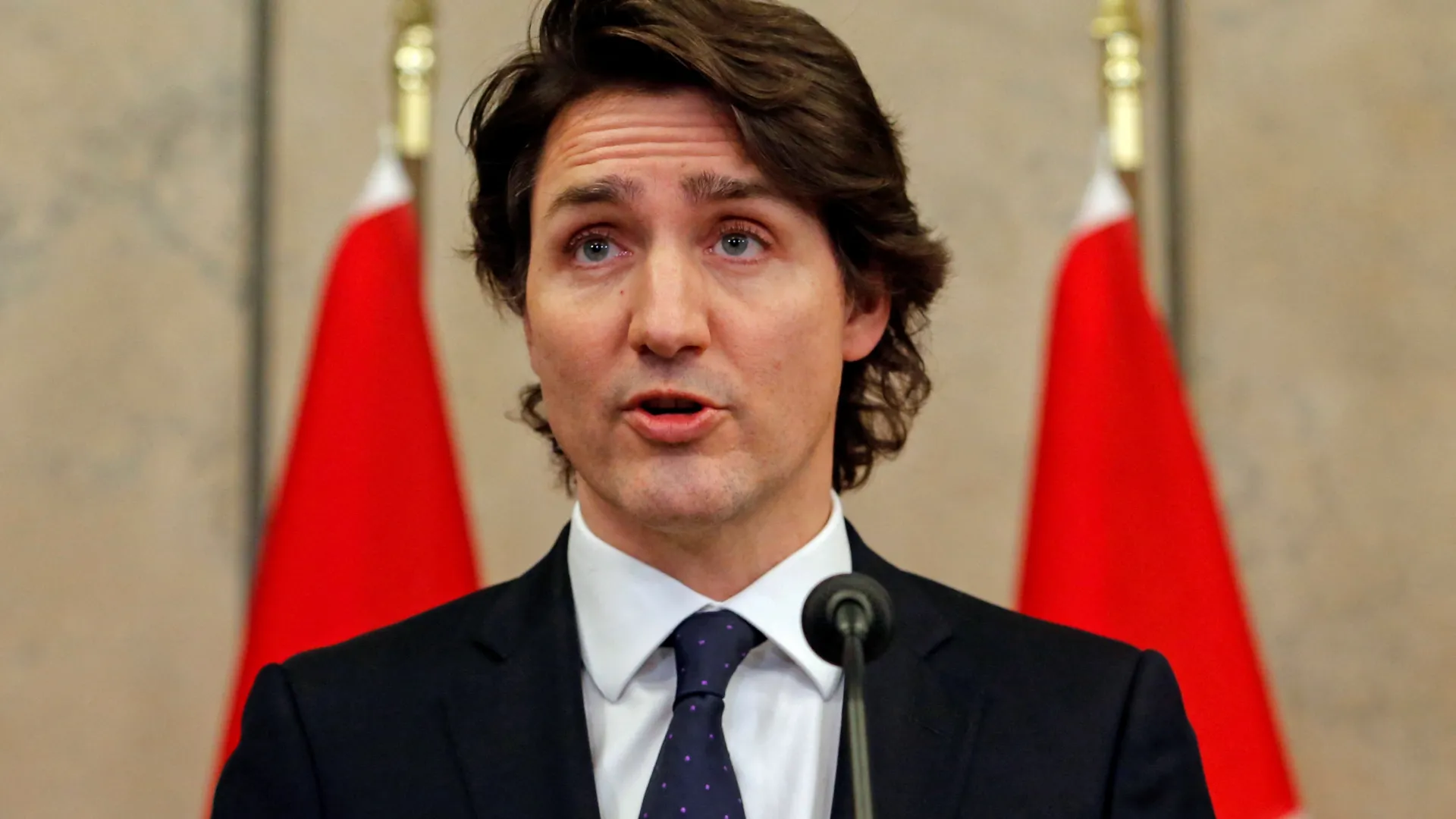 Justin Trudeau standing in front of canadian flags
